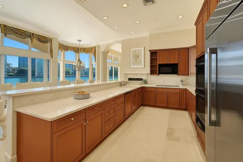a large kitchen with a large counter top a sink stainless steel appliances and cabinets