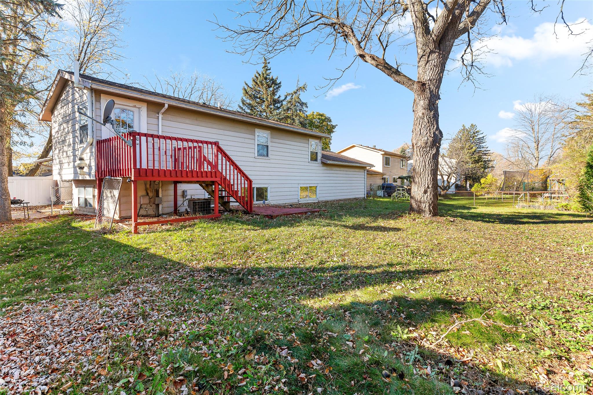 22582 Winfield Road Novi, MI 48375 - Photo 33 of 37 Expansive backyard featuring a red-stained wood deck, mature trees, and a spacious grassy area