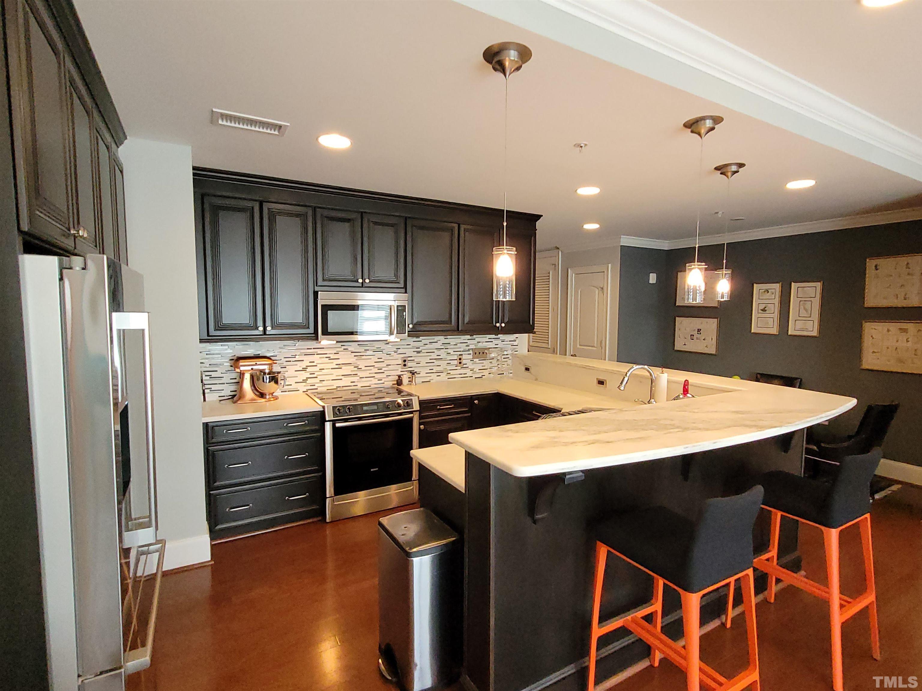 710 Independence Place, Unit 208/2C Raleigh, NC 27603 - Photo 2 of 29 a kitchen with stainless steel appliances kitchen island granite countertop a sink a stove a refrigerator and island with wooden floor