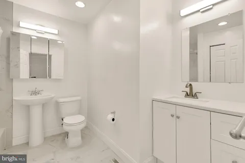 a bathroom with a toilet a sink a mirror and vanity