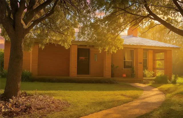 a view of yellow house with a large tree