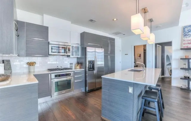 a kitchen with stainless steel appliances granite countertop wooden floor sink stove and refrigerator