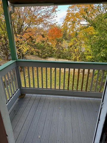 a balcony with wooden floor and trees in the back