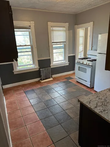 a kitchen with granite countertop a stove a sink and a microwave