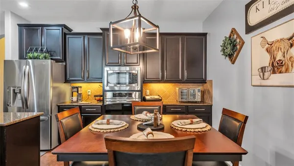 a kitchen with stainless steel appliances granite countertop a refrigerator a sink a stove and chairs
