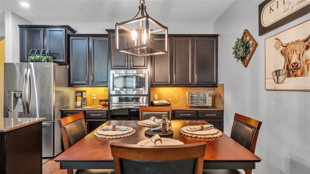 4105 Berkshire Loop Lakeland, FL 33813 - Photo 15 of 41 a kitchen with stainless steel appliances granite countertop a refrigerator a sink a stove and chairs