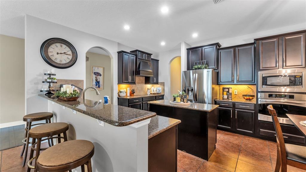4105 Berkshire Loop Lakeland, FL 33813 - Photo 16 of 41 a kitchen with stainless steel appliances kitchen island granite countertop a refrigerator a stove a sink and dishwasher