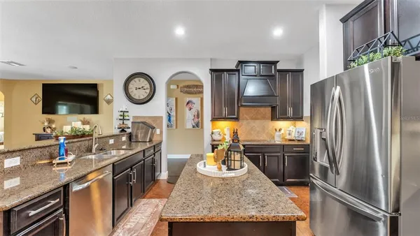 a kitchen with stainless steel appliances granite countertop a refrigerator a stove and a dining table with wooden floor