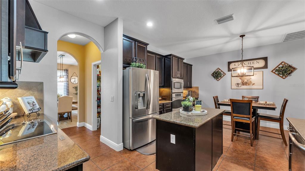 4105 Berkshire Loop Lakeland, FL 33813 - Photo 20 of 41 a kitchen with stainless steel appliances granite countertop a refrigerator a stove and a dining table with wooden floor
