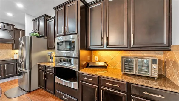 a kitchen with stainless steel appliances granite countertop a refrigerator and a stove top oven