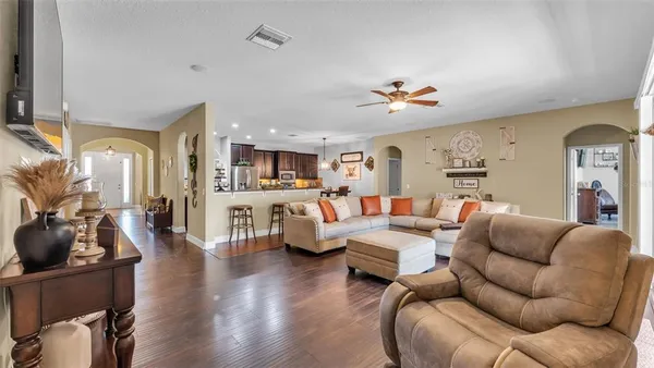 a living room with furniture kitchen view and a wooden floor