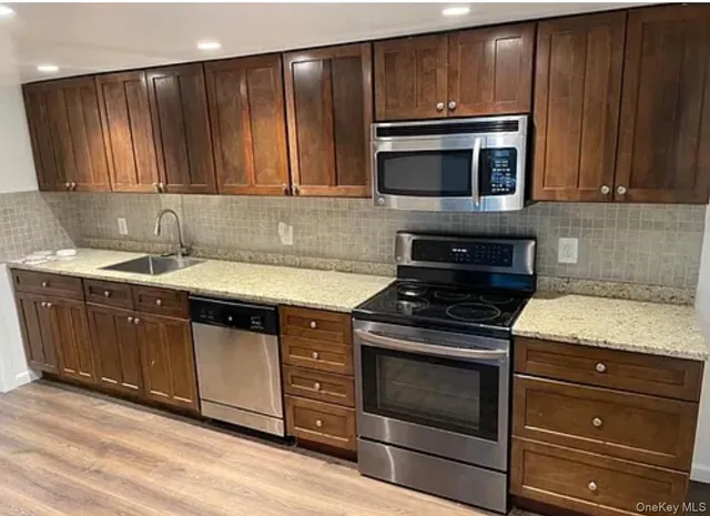 a kitchen with granite countertop wooden cabinets and a stove top oven