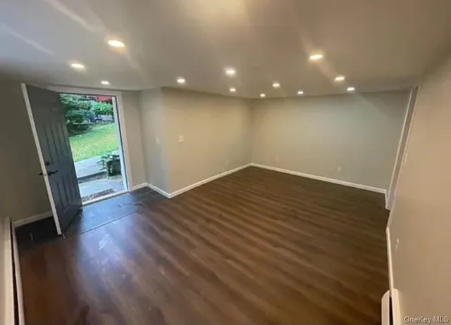 an empty room with wooden floor and entrance
