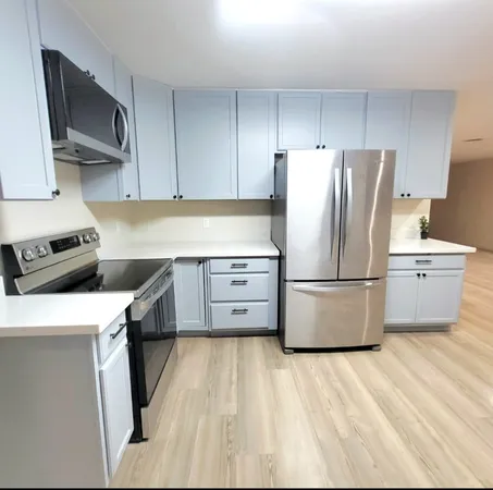 a kitchen with a refrigerator a stove top oven a sink and dishwasher with wooden floor