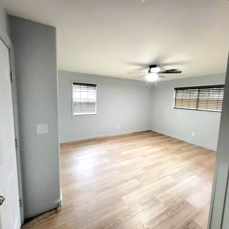 an empty room with wooden floor and windows