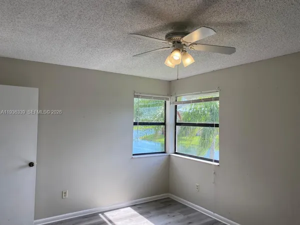 an empty room with wooden floor fan and windows