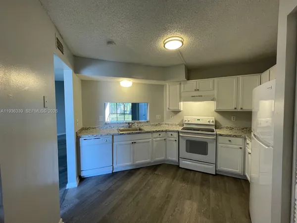 a large kitchen with a white stove top and refrigerator