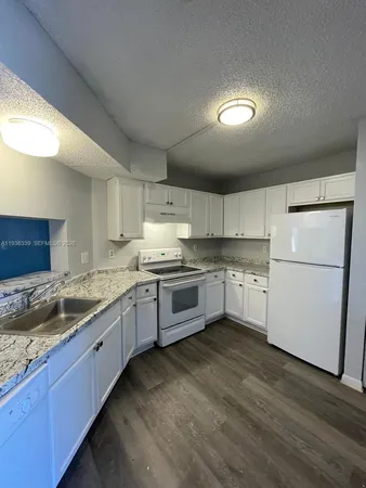 a white refrigerator freezer and a stove sitting inside of a kitchen