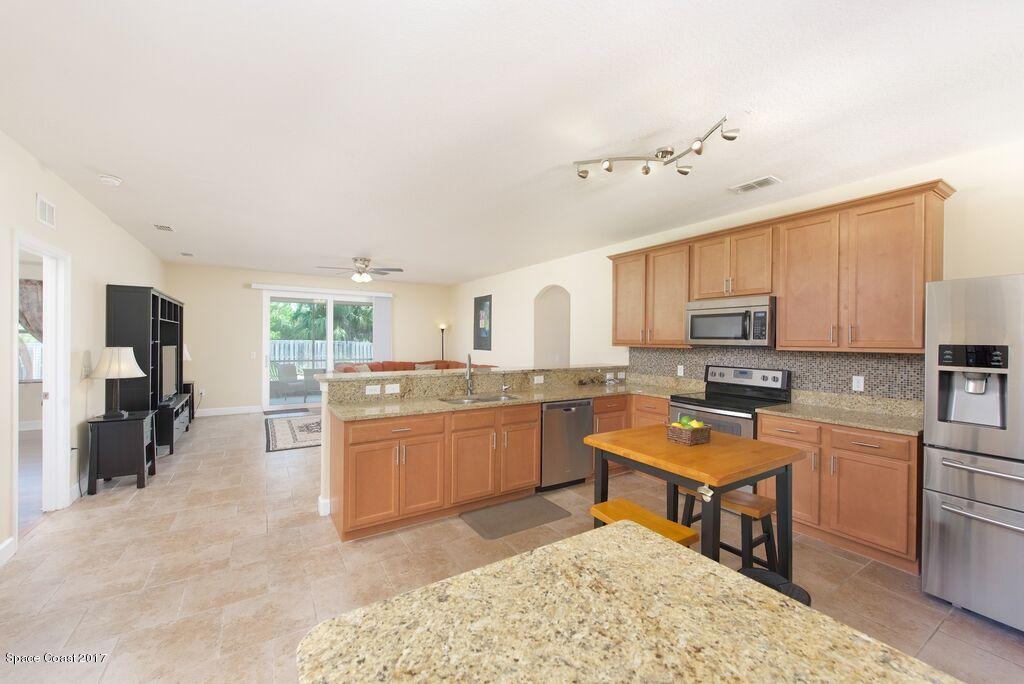 249 Franzing Street Palm Bay, FL 32908 - Photo 6 of 20 a kitchen with a refrigerator a stove top oven a sink dishwasher and wooden cabinets