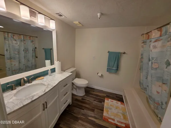 a bathroom with a granite countertop sink a toilet a mirror and shower