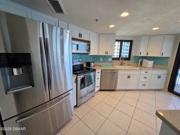a kitchen with white cabinets stainless steel appliances and a window