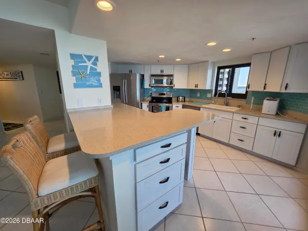 a kitchen with white cabinets appliances and furniture