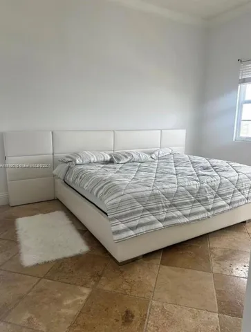 a bedroom with a bed and a lamp on the dresser