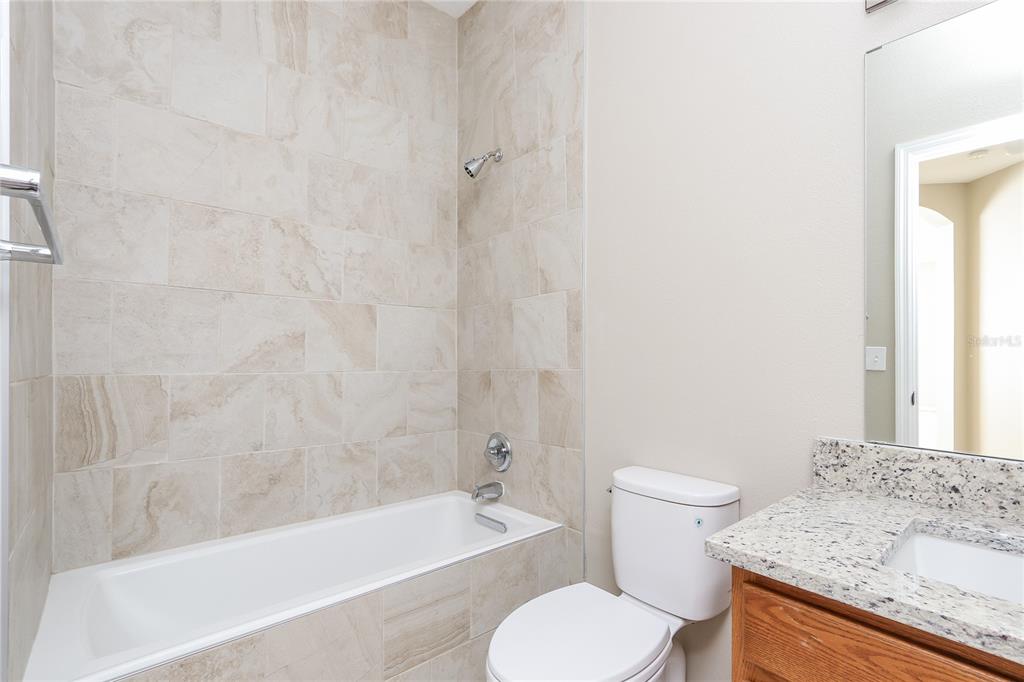 6239 Blue Runner Court Lakewood Ranch, FL 34202 - Photo 14 of 15 a bathroom with a granite countertop toilet a sink and bathtub