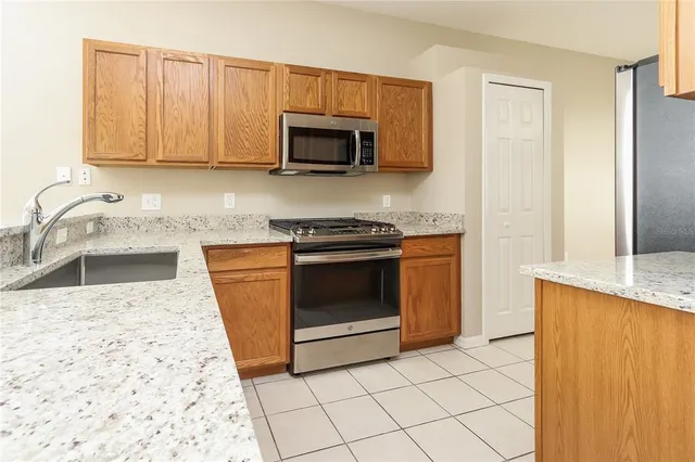 a kitchen with granite countertop a sink a stove top oven and cabinets