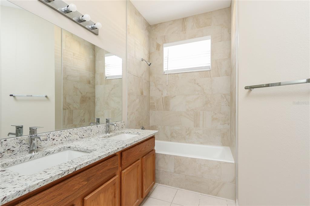 6239 Blue Runner Court Lakewood Ranch, FL 34202 - Photo 10 of 15 a bathroom with a granite countertop sink a mirror and a bathtub