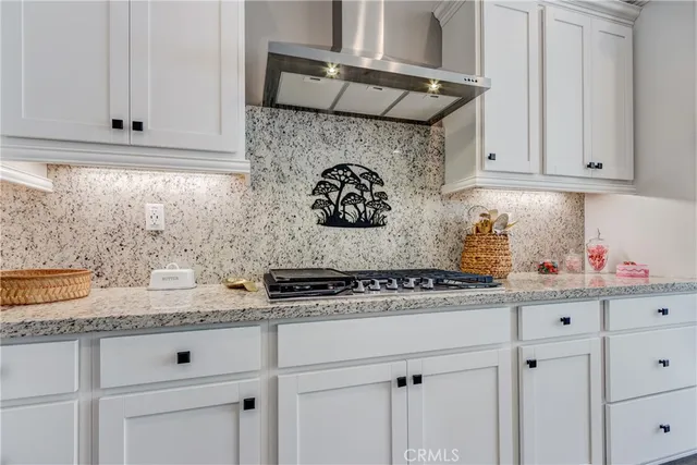 a kitchen with stainless steel appliances kitchen island granite countertop a stove top oven a sink a refrigerator and white cabinets