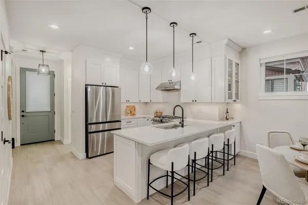 a kitchen with stainless steel appliances granite countertop a sink a refrigerator a stove a kitchen island with chairs and cabinets