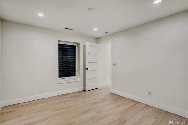 a view of an empty room with wooden floor and closet