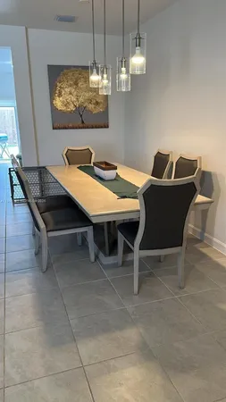 a room with furniture a chandelier and view of kitchen