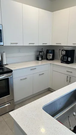 a kitchen with stainless steel appliances granite countertop a sink a stove and white cabinets
