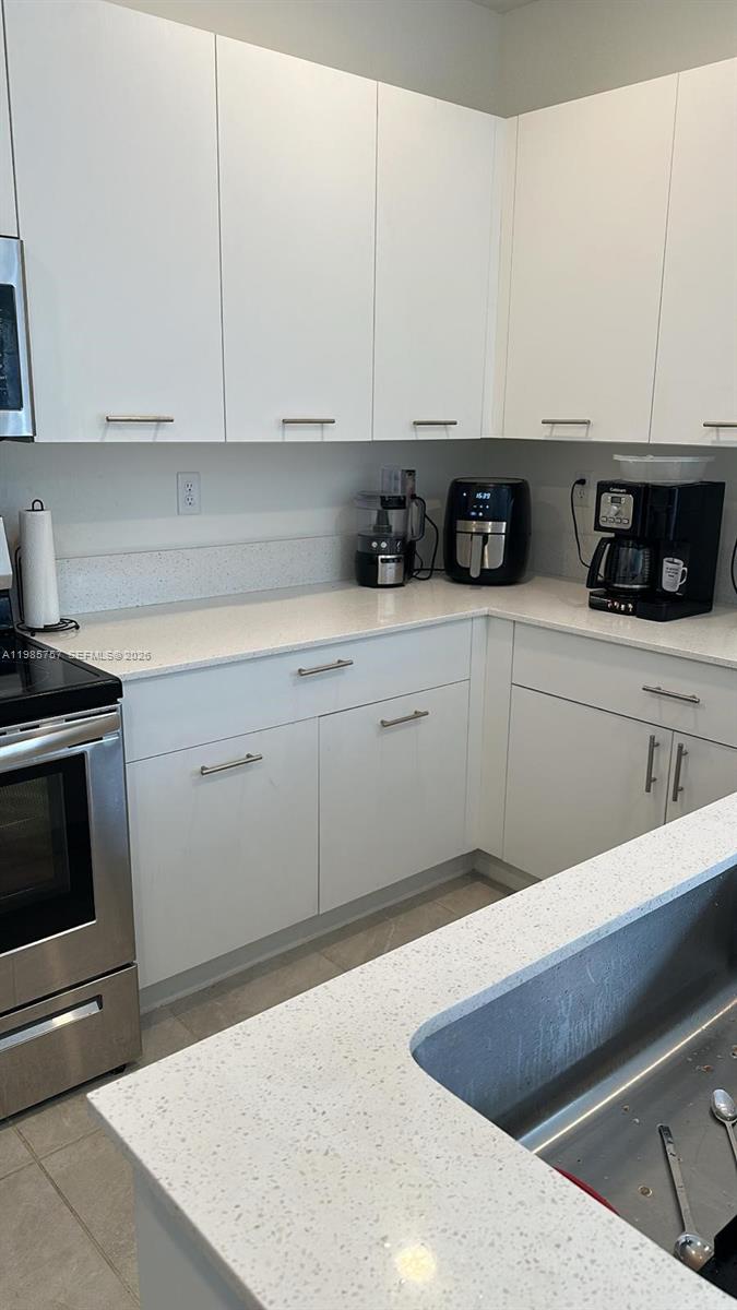 12221 Northwest 23rd Place Miami, FL 33167 - Photo 8 of 17 a kitchen with stainless steel appliances granite countertop a sink a stove and white cabinets