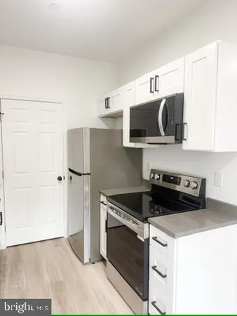 a kitchen with granite countertop a refrigerator stove and white cabinets