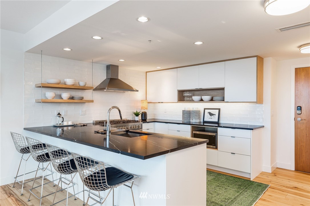 1420 Terry Avenue, Unit 2602 Seattle, WA 98101 - Photo 13 of 40 a kitchen with stainless steel appliances granite countertop a sink a stove a refrigerator and white cabinets with wooden floor