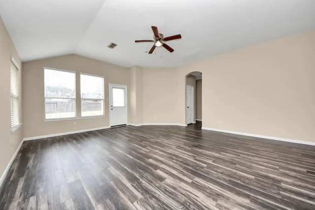 a view of empty room with wooden floor and window