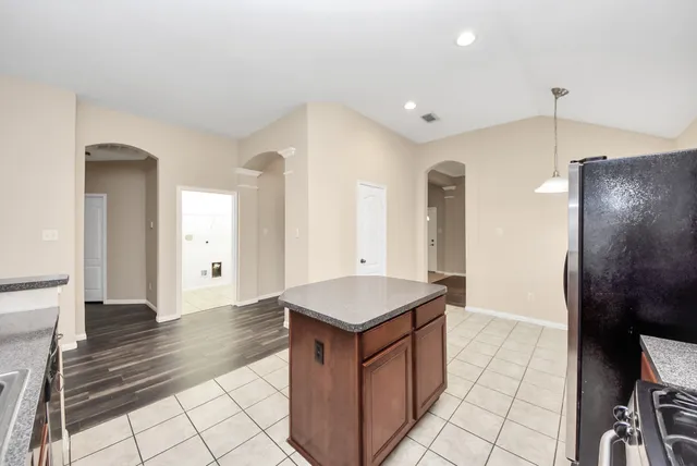 a large kitchen with kitchen island granite countertop a sink a counter top space and cabinets