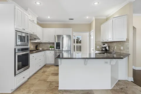 a kitchen with stainless steel appliances granite countertop a stove a sink and a refrigerator