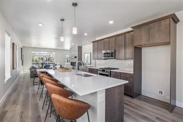 a kitchen with stainless steel appliances granite countertop a table chairs sink refrigerator and microwave