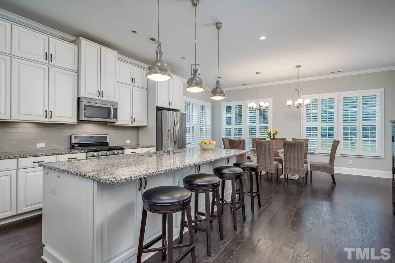3608 Julia Lane Raleigh, NC 27609 - Photo 2 of 30 a kitchen with stainless steel appliances granite countertop a stove a refrigerator a kitchen island a dining table and chairs with wooden floor