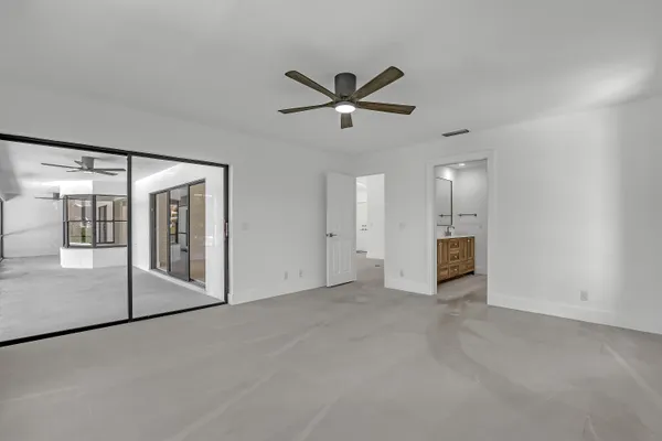an empty room with windows and ceiling fan