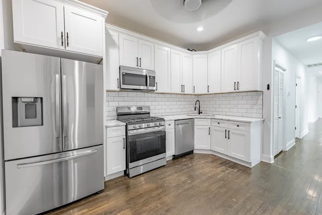 a kitchen with stainless steel appliances white cabinets and a refrigerator