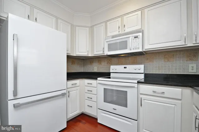 a kitchen with white cabinets and white appliances