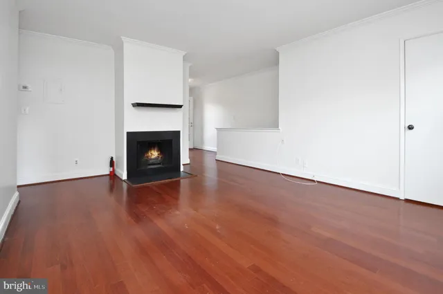 a view of an empty room with wooden floor and a fireplace
