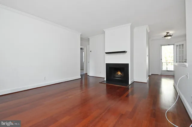 a view of an empty room with wooden floor fireplace and a window