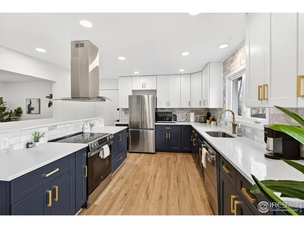 a kitchen with kitchen island granite countertop a sink counter top space a large refrigerator and cabinets