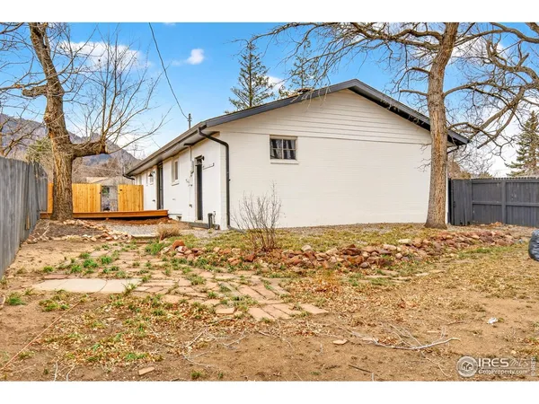 a view of a house with floor to ceiling windows and a yard with wooden fence